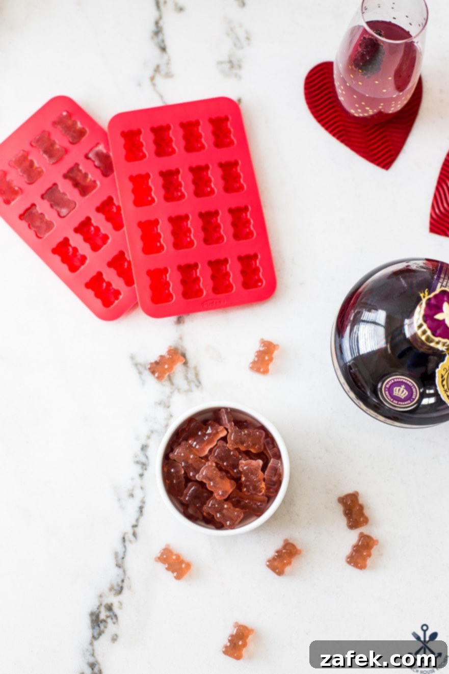 Overhead view of a bowl filled with various Chambord boozy gummy bears, surrounded by silicone gummy bear molds, ready for production.