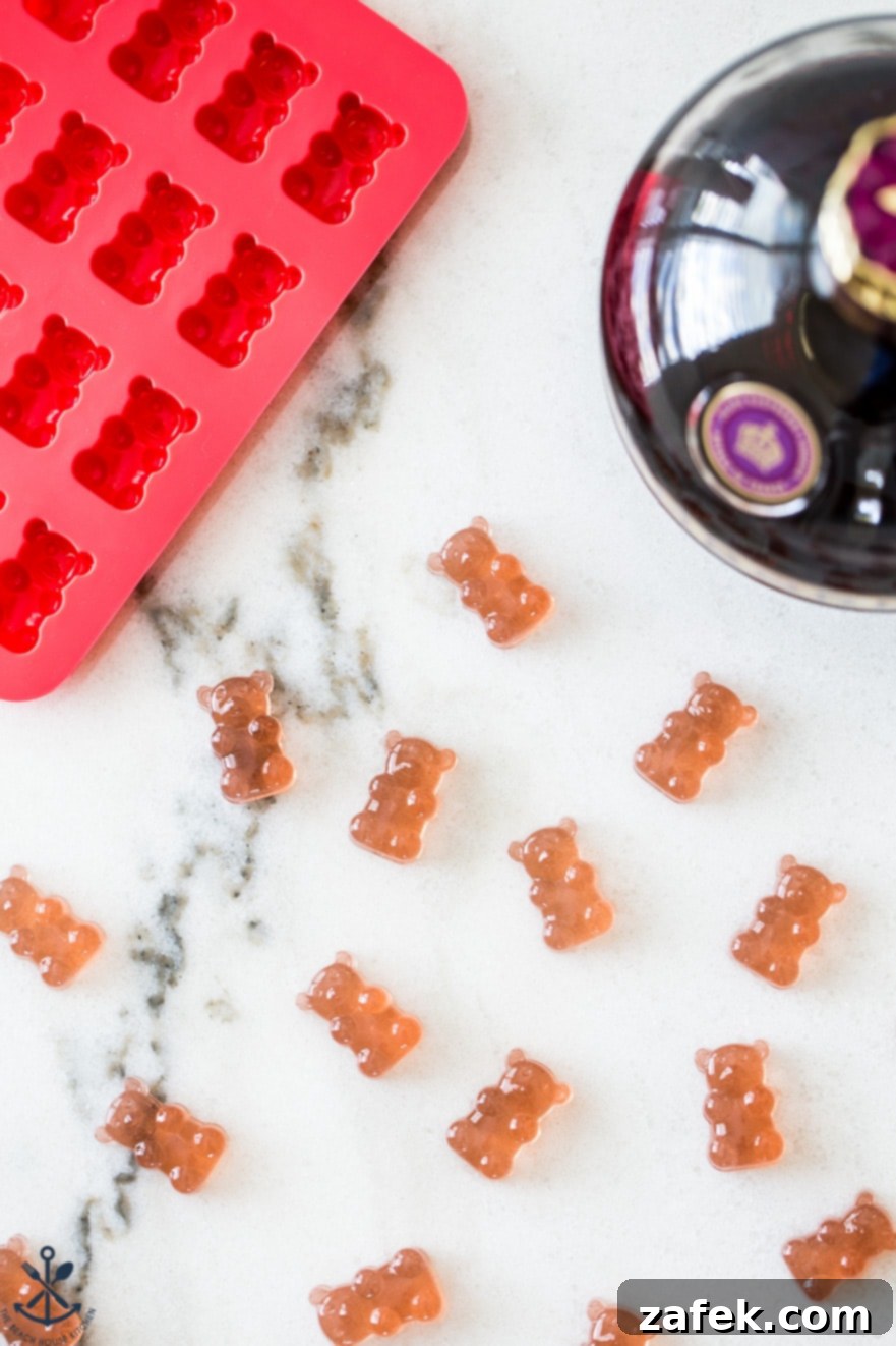 Close-up overhead shot of glistening Chambord gummy bears on a marble surface, with a silicone mold and a Chambord bottle in the background, showcasing the finished product.