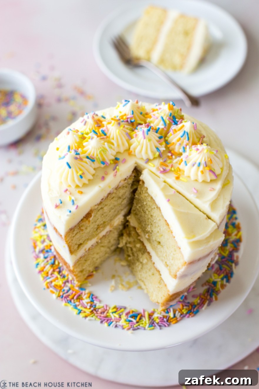 Bright yellow Lemon Layer Cake decorated with lemon slices and sprinkles