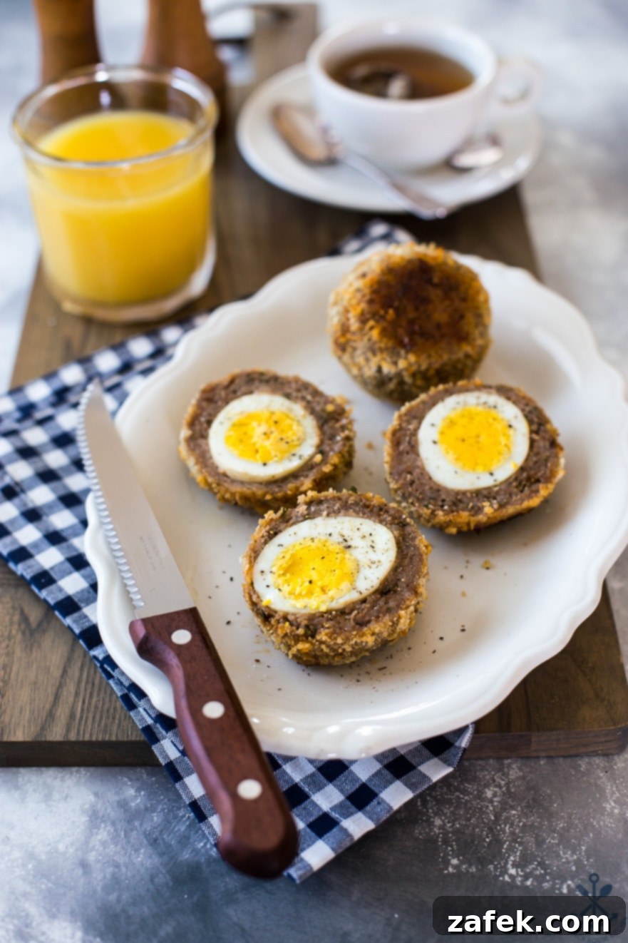 A plate of halved scotch eggs with a knife on a blue and white checked napkin