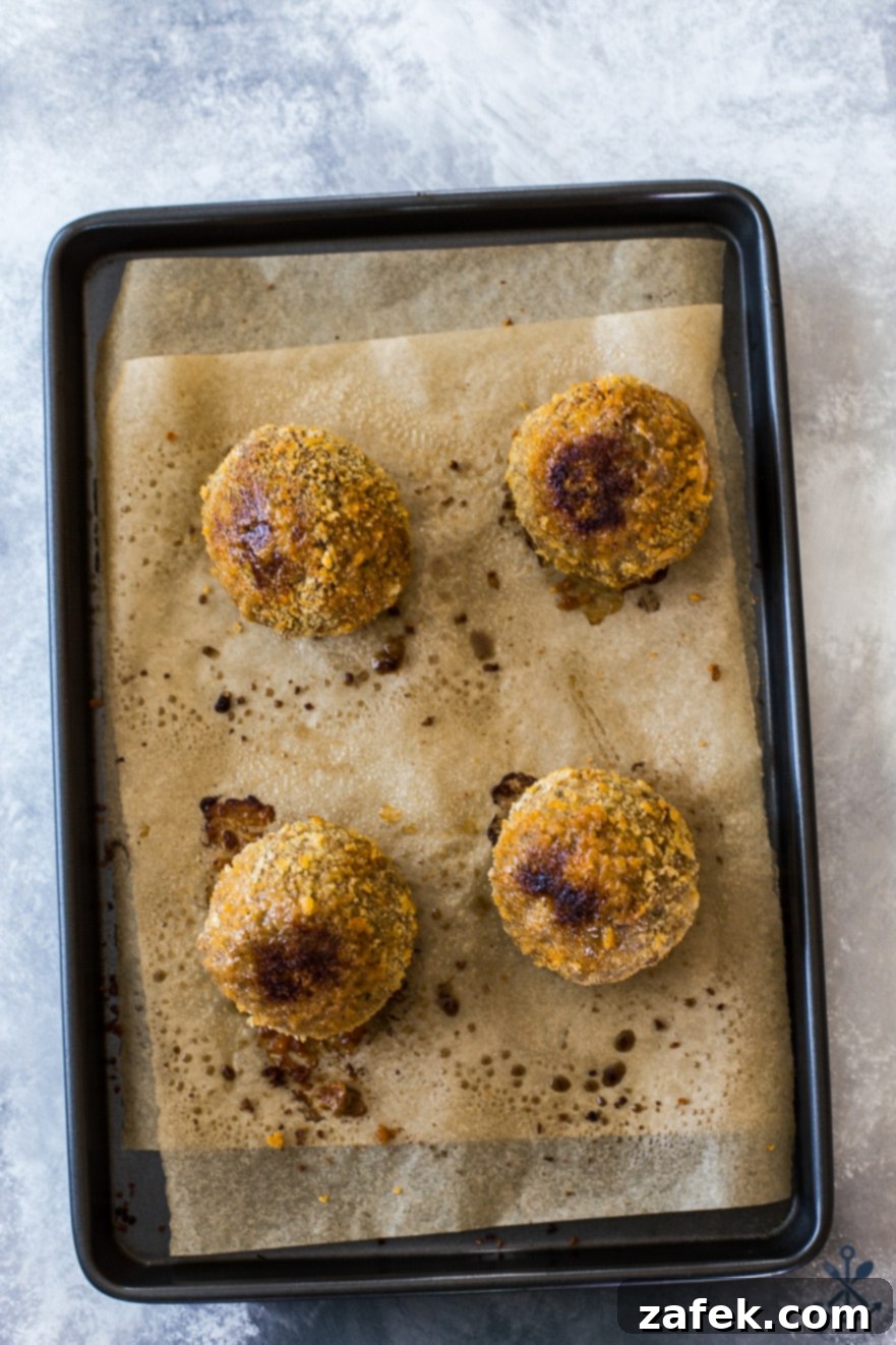 Overhead photo of 4 scotch eggs on a baking sheet lined with parchment paper