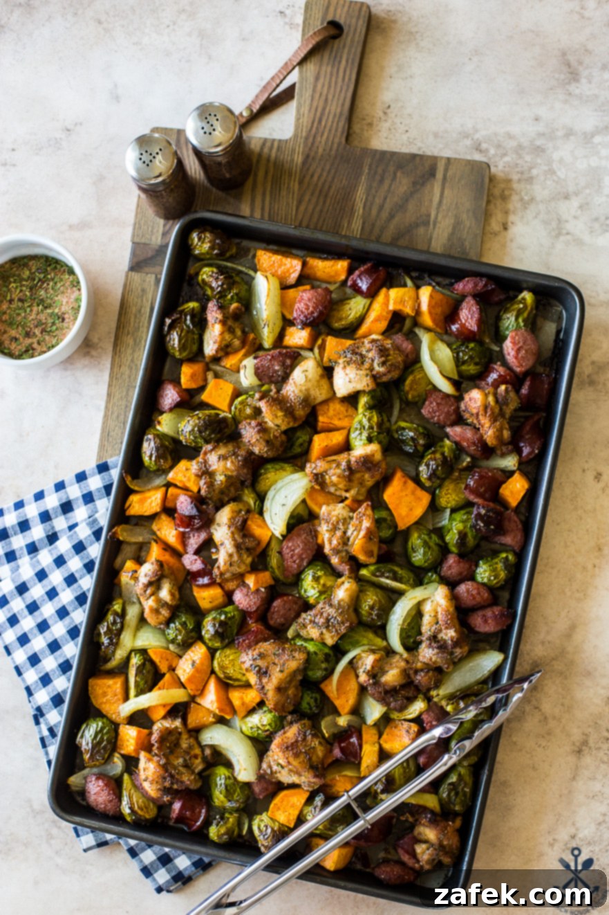 Overhead photo of sheet pan filled with jerk chicken, sweet potatoes, onions and Brussels sprouts, freshly baked and vibrant