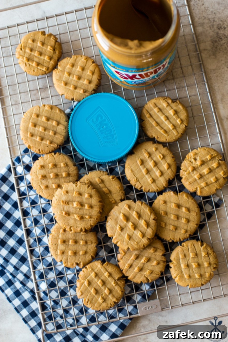 Overhead photo of peanut butter cookies on a wire rack with a jar of peanut butter and a blue lid
