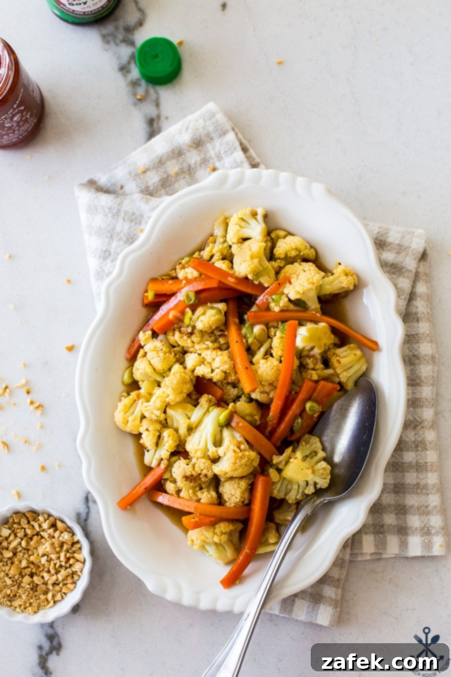 Overhead photo of Roasted Asian Cauliflower and Carrots on an oval white plate, ready to be served