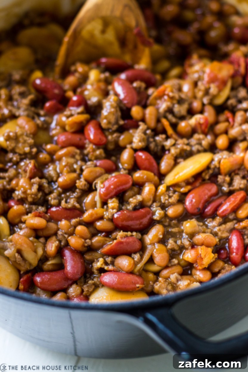 Hearty Three-Bean Casserole 5 Up close photo of a bean casserole in a dark blue Dutch oven pot, highlighting the rustic appeal.