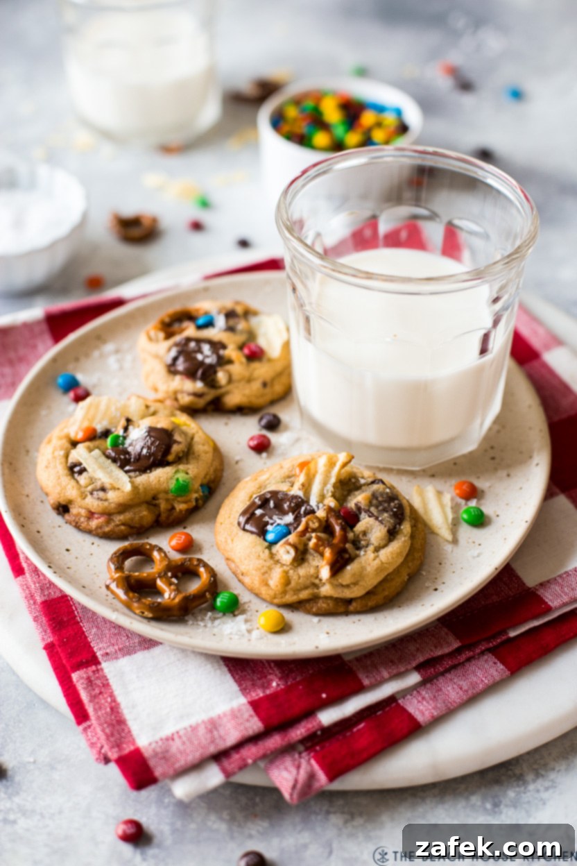Kitchen Sink Cookies 3 A plate of two perfectly baked Kitchen Sink Cookies with a glass of milk on a rustic wooden surface