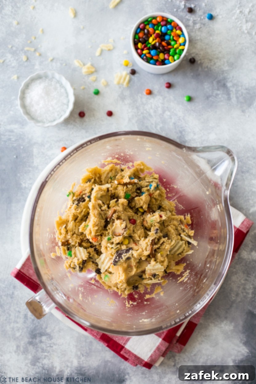 Kitchen Sink Cookies 5 Overhead photo of rich, speckled cookie dough in a clear glass bowl, ready for baking