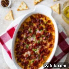 Overhead photo of a white oval dish filled with baked pepperoni dip and crackers around