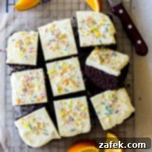 Overhead of the photo of iced chocolate cake surrounded by orange slices and a sharp knife