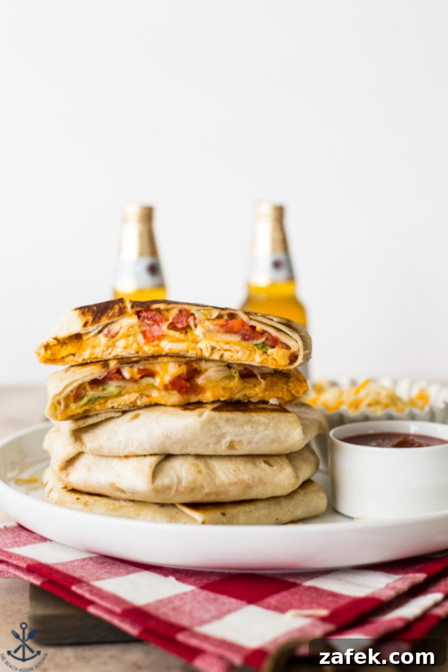 Buffalo Chicken Ultimate Crispy Wraps 2 A stack of golden-brown Buffalo Chicken Crunchwrap Supremes, perfectly grilled, with frosty beers in the background, suggesting a festive game day atmosphere.