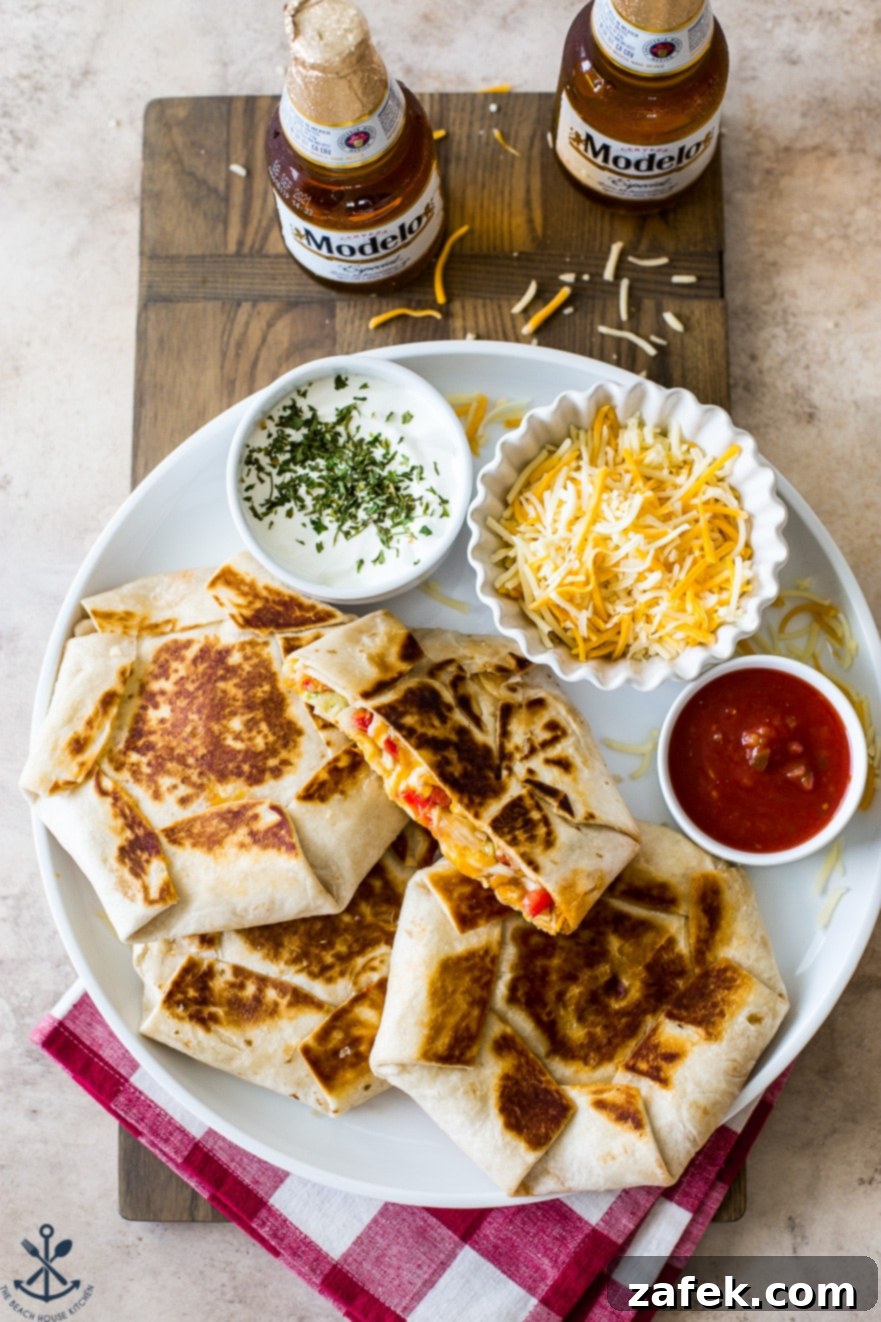 Buffalo Chicken Ultimate Crispy Wraps 4 A vibrant overhead display of three Buffalo Chicken Crunchwrap Supremes on a white platter, accompanied by fresh sour cream, shredded cheese, and a spoonful of red salsa, showcasing their irresistible appeal.