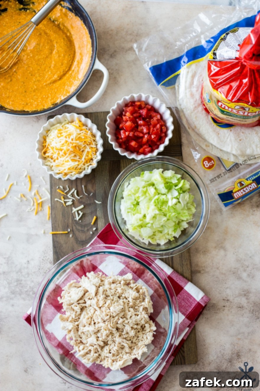 Buffalo Chicken Ultimate Crispy Wraps 5 An overhead view of various ingredients for buffalo chicken crunchwraps, neatly arranged in glass bowls on a rustic wooden board, including shredded chicken, cheese, lettuce, tomatoes, and sauces.