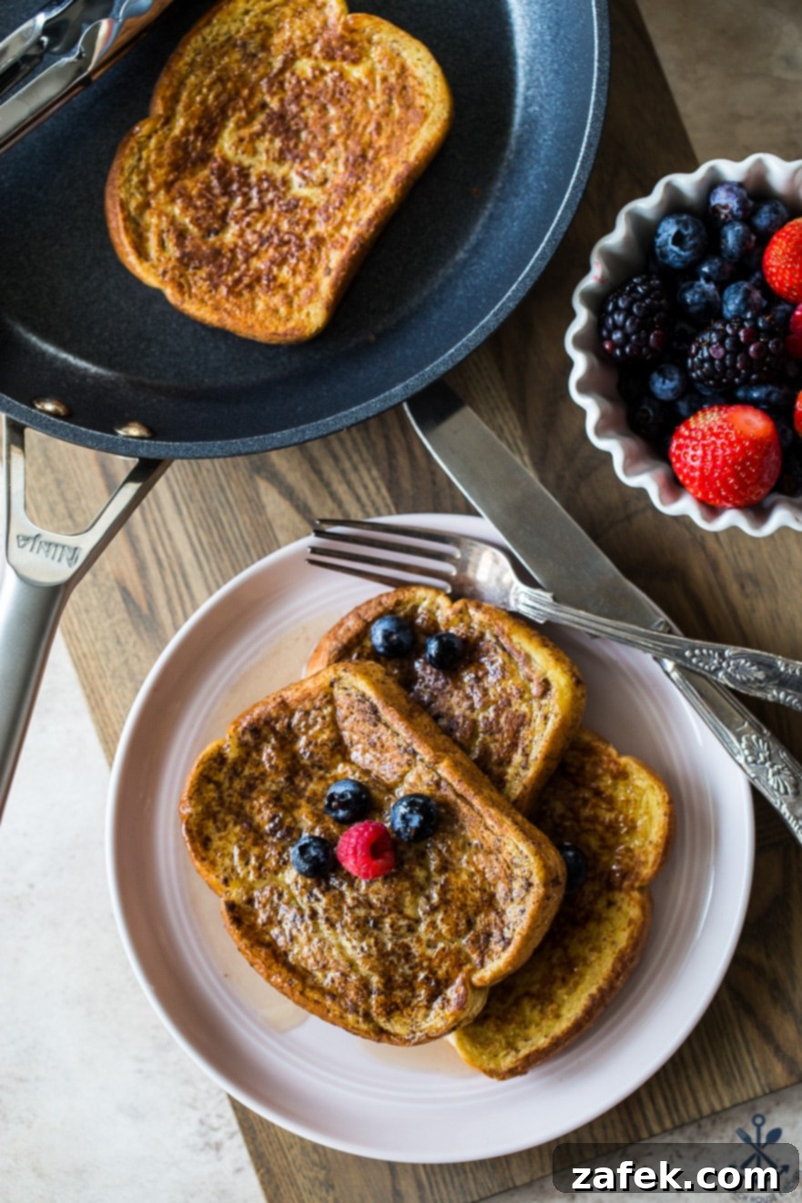 Aromatic Chai French Toast 2 Overhead photo of french toast slices on a plate with berries and a fork and knife