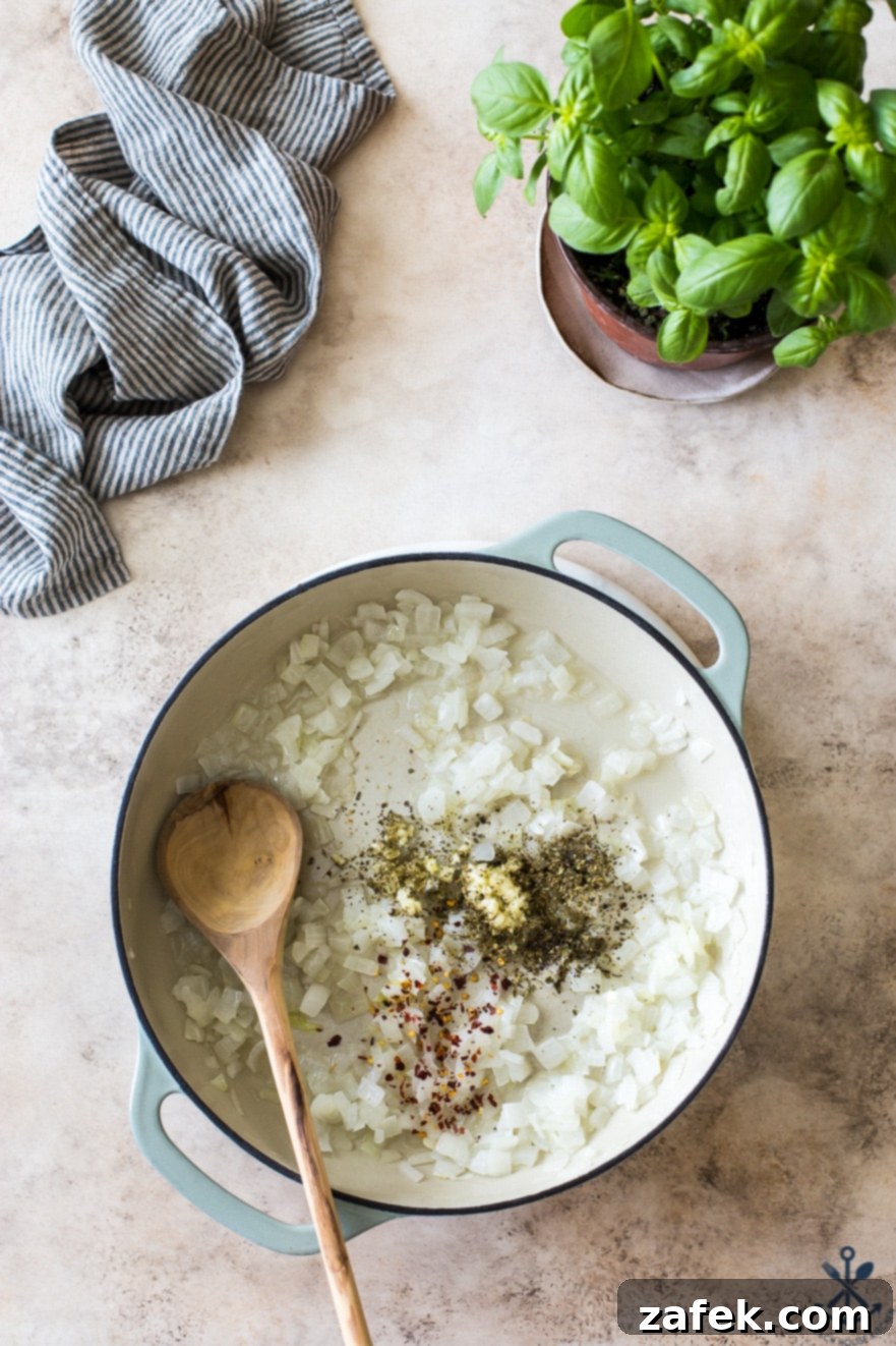 Pink Sauce Penne 5 Overhead photo of a round baking dish containing finely chopped yellow onions and a vibrant mix of aromatic spices, prior to cooking
