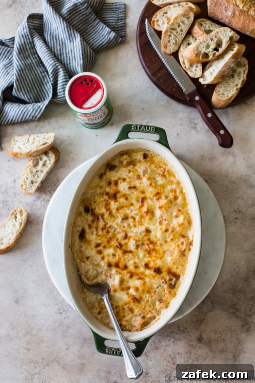 Creole Shrimp Kick 2 Overhead photo of a shrimp dip in an oval dish surrounded by baguette slices, ready to be served at a party.