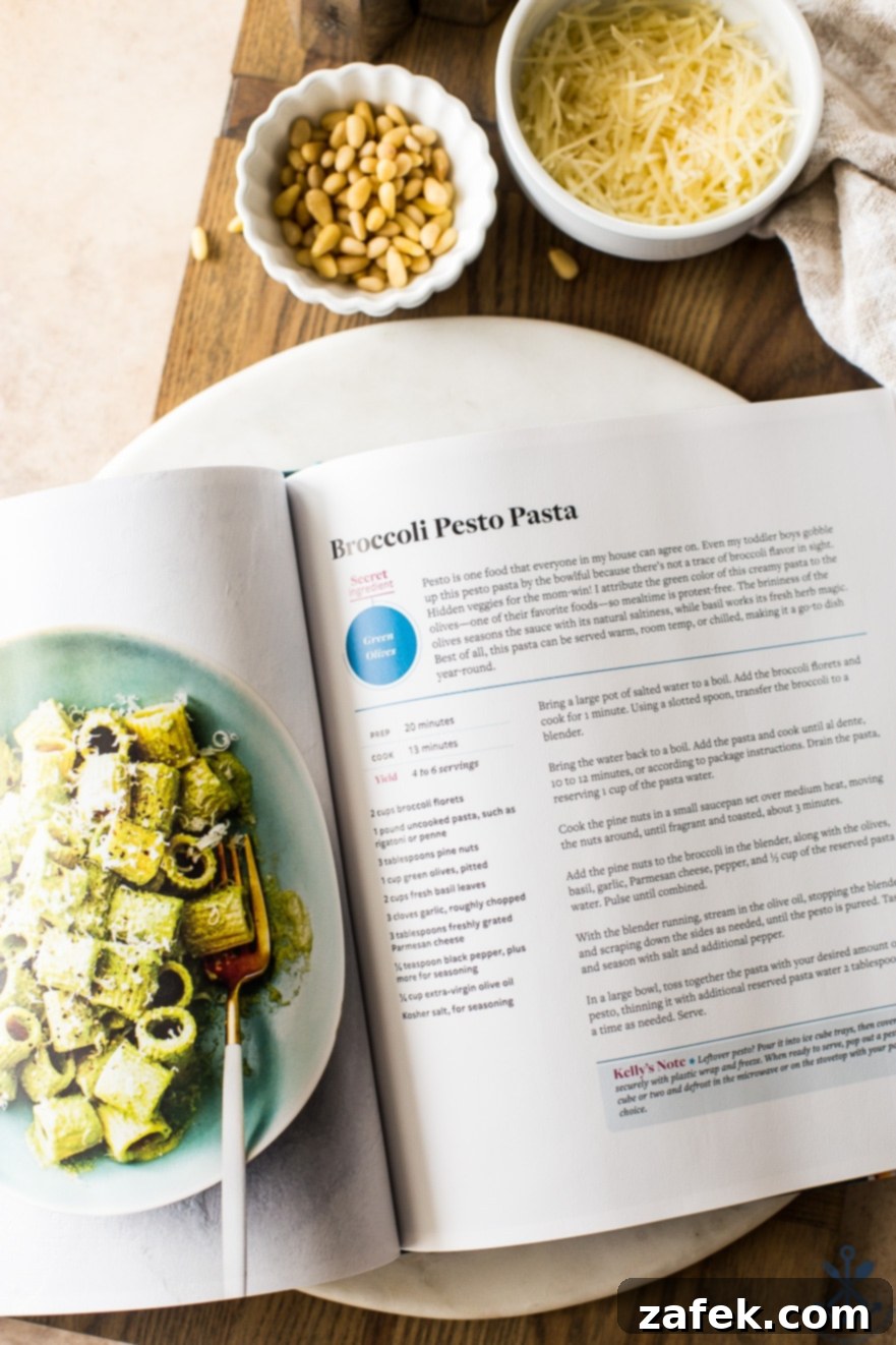 Overhead photo of The Secret Ingredient Cookbook open to the page displaying the Broccoli Pesto Pasta recipe, inviting readers to explore