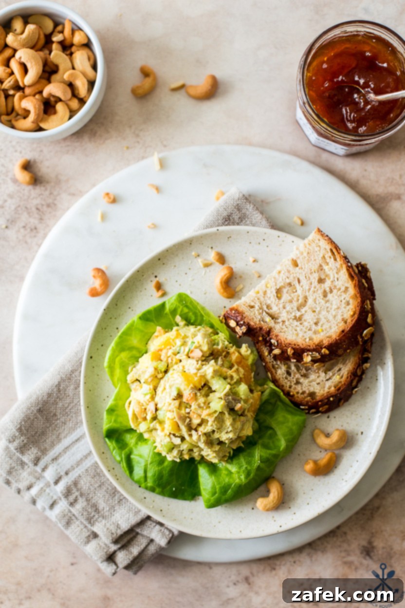 Overhead photo of a plate with curried chicken salad on a piece of lettuce, served alongside two slices of whole wheat bread