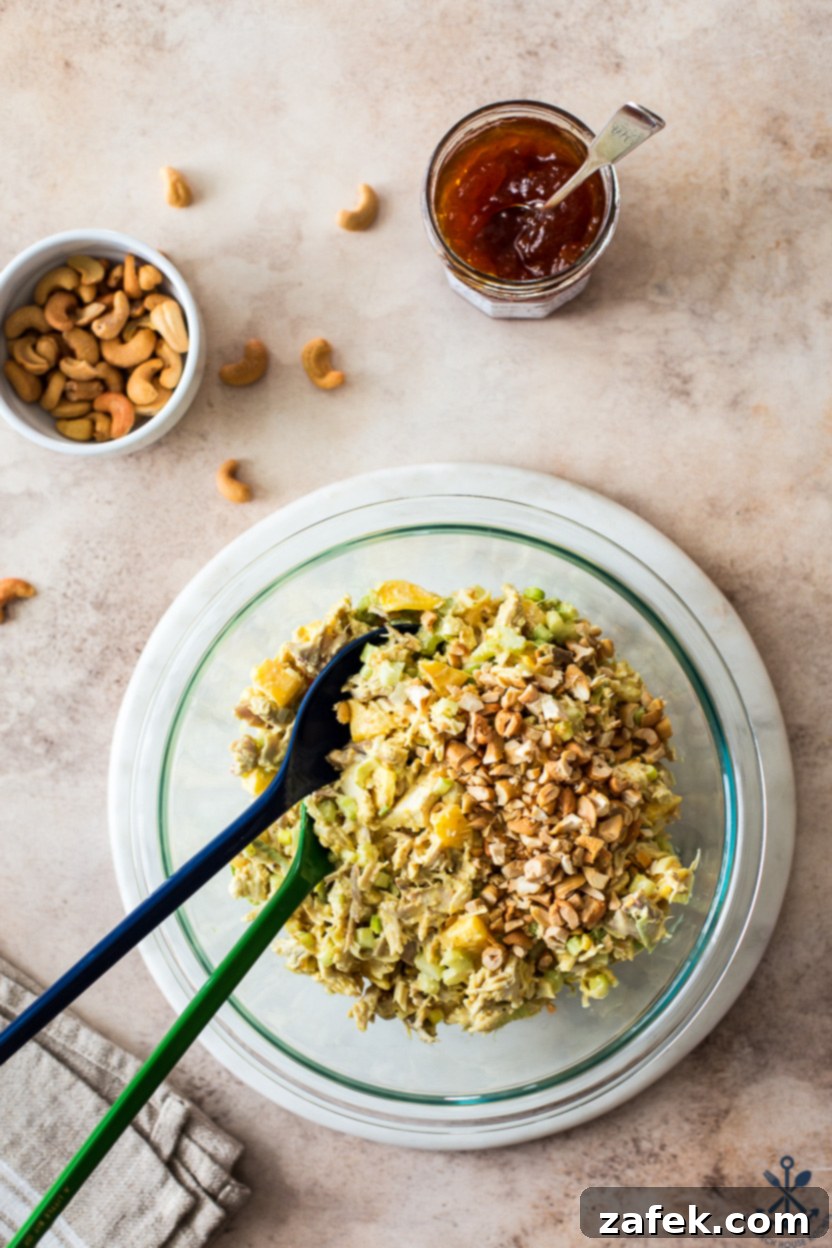 Overhead photo of a bowl of curried chicken salad, beautifully topped with a generous sprinkle of chopped cashews