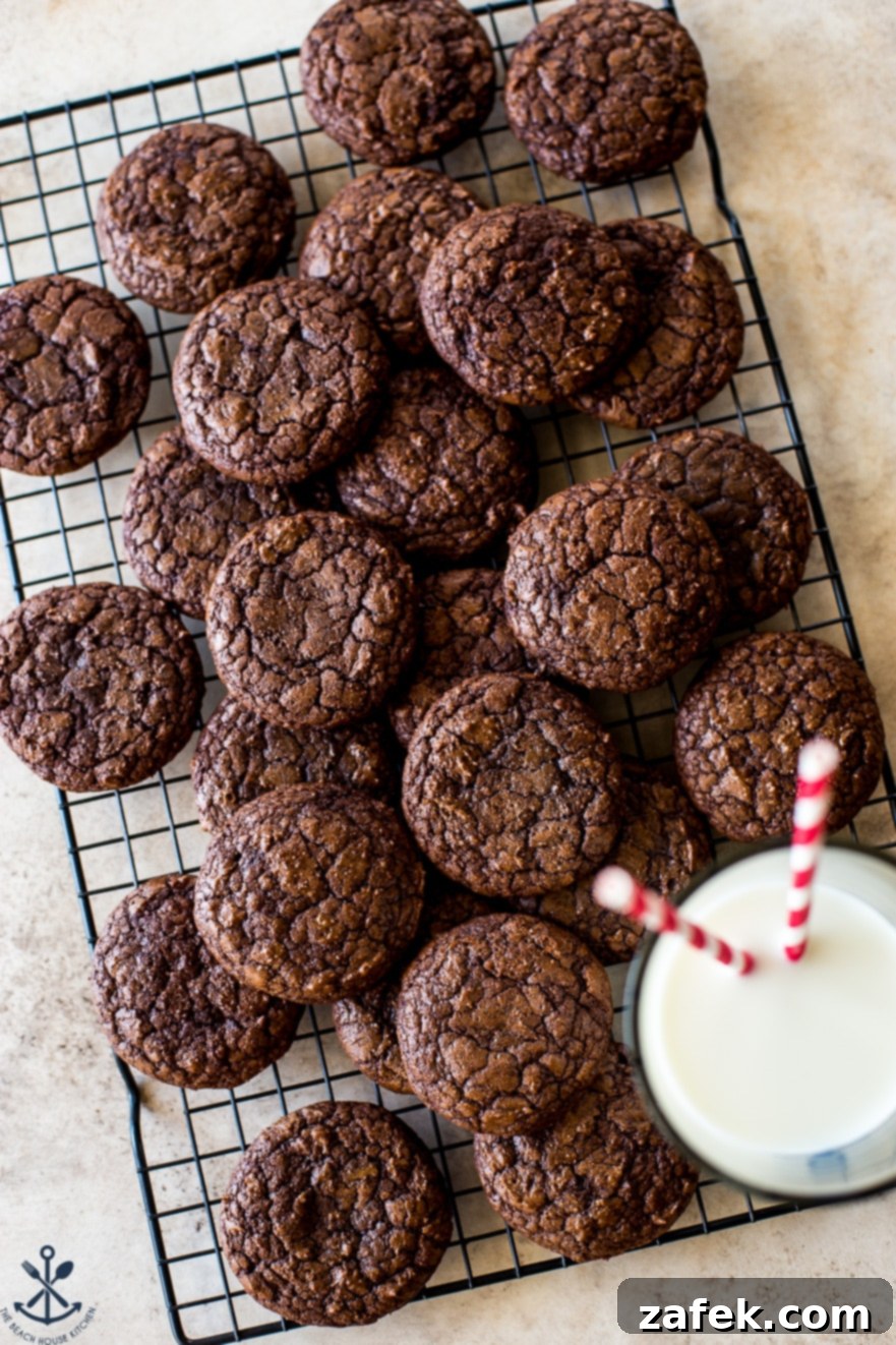 Decadent Fudgy Brownie Cookies 5 An overhead photo of a wire rack filled with dark chocolate cookies and a glass of milk