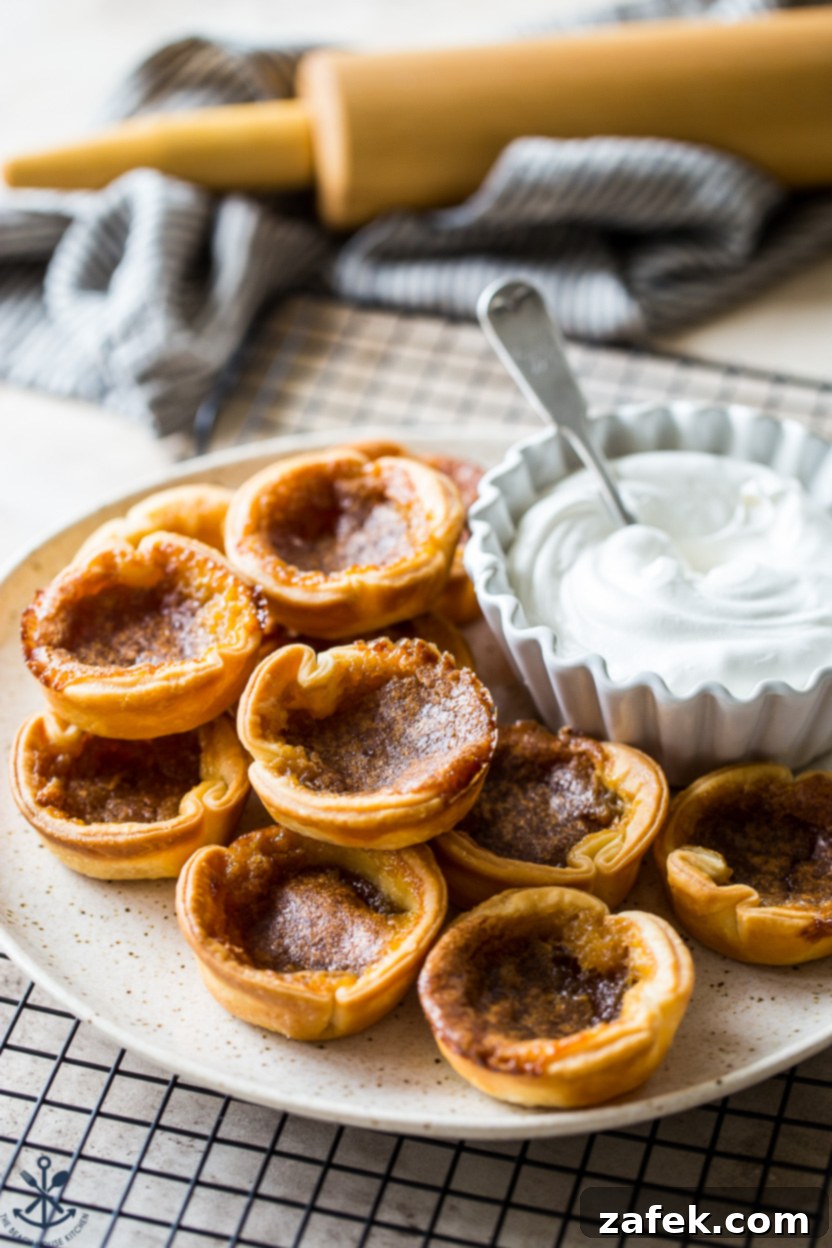A plate of butter tarts with a bowl of whipped cream