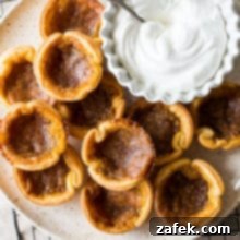 Candian Butter Tarts on a plate with some whipped cream in a bowl