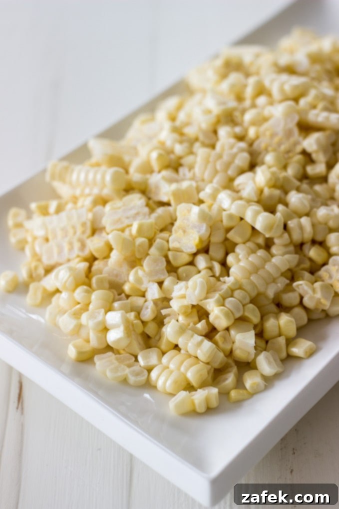 Creamy Cajun Corn Maque Choux 4 Close-up shot of Corn Maque Choux simmering in a pan, showcasing the vibrant colors of corn, peppers, and onions, with crispy bacon visible.