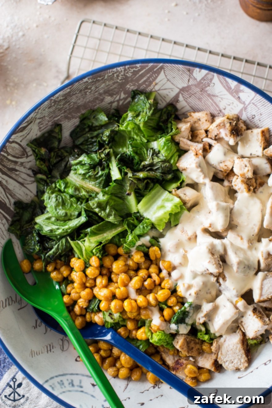 Chargrilled Chicken Caesar with Roasted Chickpea Crunch 4 Overhead perspective of a bountiful Grilled Chicken Caesar Salad bowl, featuring crisp romaine, golden roasted chickpeas, and juicy grilled chicken, all brought together with a delectable Caesar dressing.