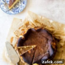 San Sebastian Burnt Cheesecake 9 Overhead photo of Burnt Basque Cheesecake on parchment paper with a bowl of strawberries and a slice on a plate with a fork