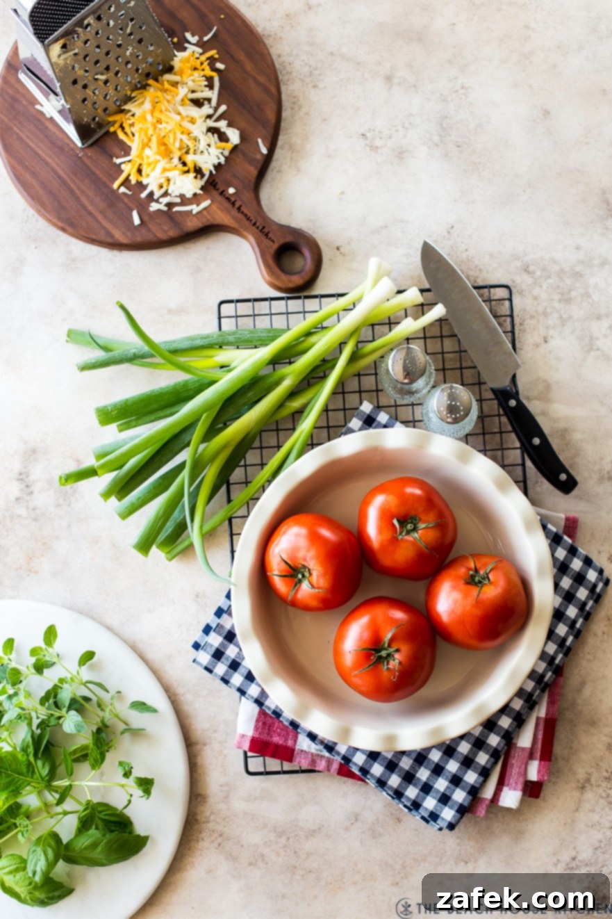 Rustic Summer Tomato Pie 4 Overhead photo of four tomatoes in a pie plate with green onions shredded cheese and basil and oregano in the background