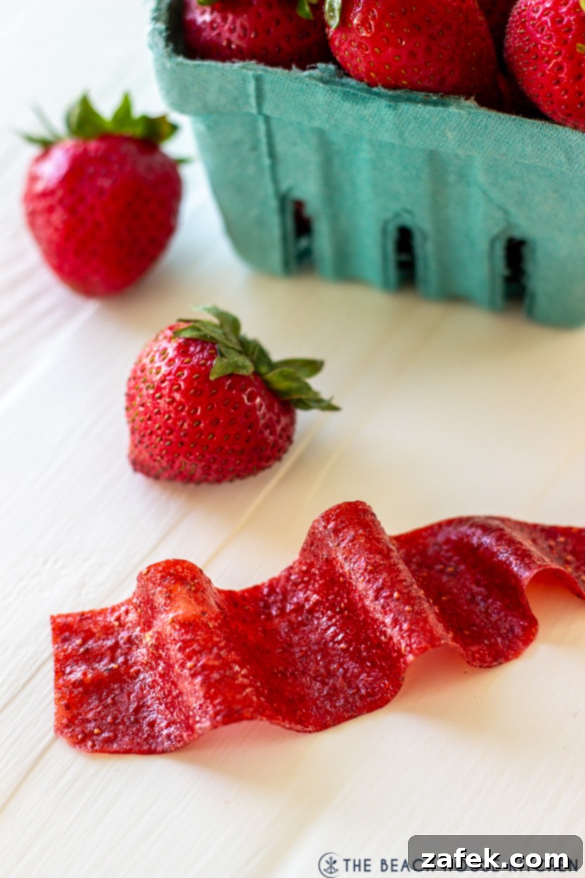 Strawberry Swirls for School Days 3 Up close photo of a strawberry fruit roll-up with fresh whole strawberries scattered around it