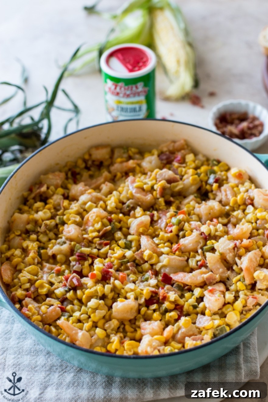 A baking dish filled with vibrant corn maque choux, featuring succulent shrimp and colorful vegetables.