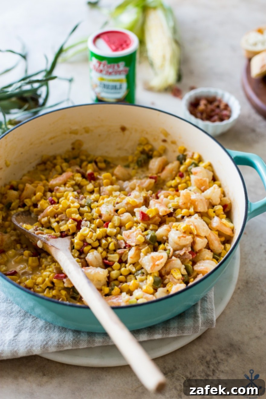 Up close photo of a vibrant corn dish with shrimp in a beautiful blue shallow Dutch oven, showcasing its rich texture.