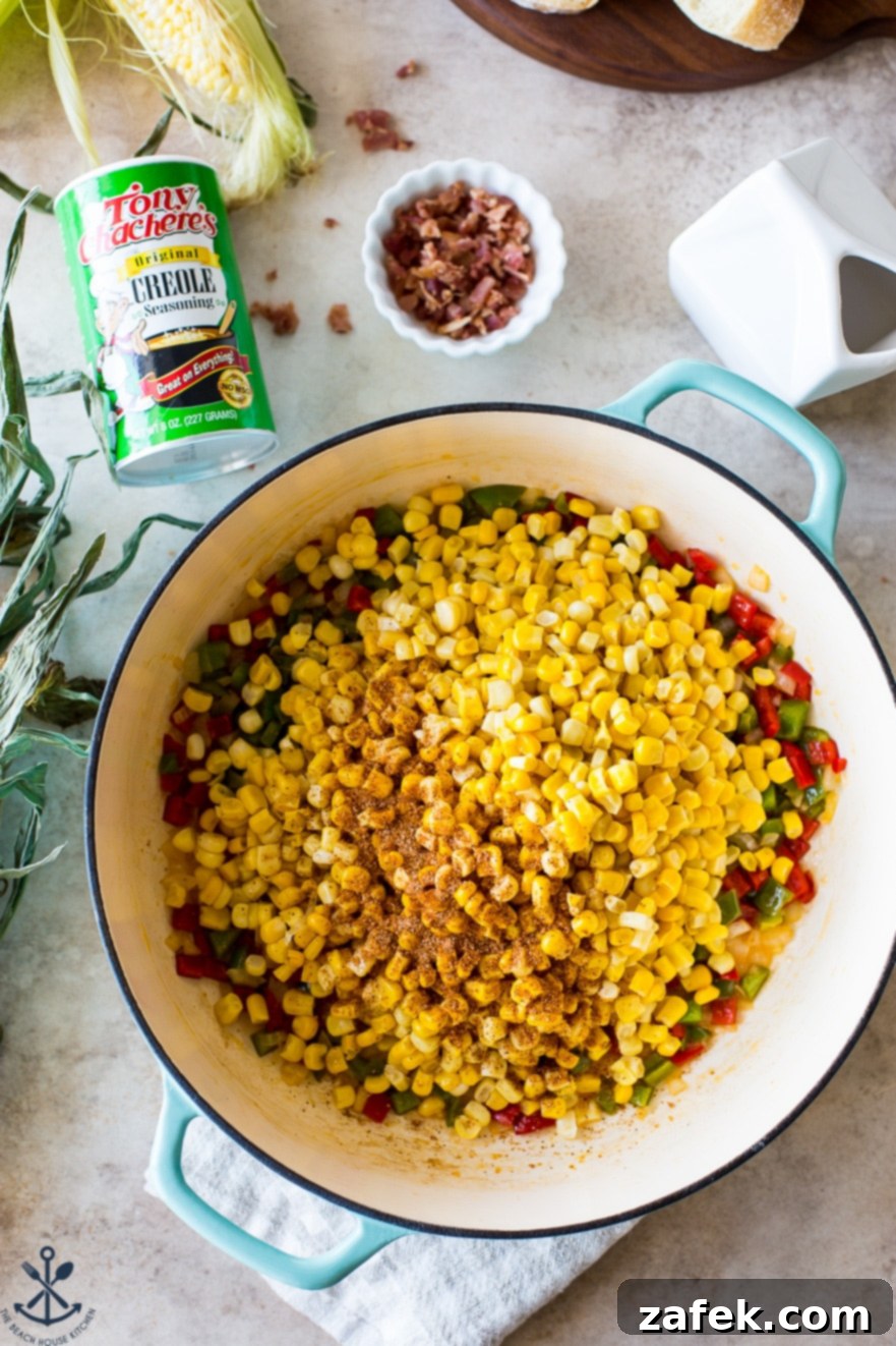 Overhead photo of a baking dish filled with corn, peppers, and onions, simmering gently.