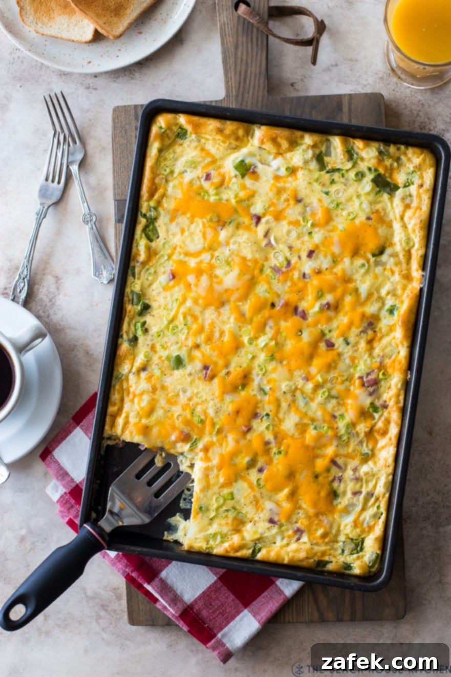 Overhead photo of a Sheet Pan Denver Omelette, beautifully cooked and ready to serve, showcasing vibrant peppers, ham, and melted cheese