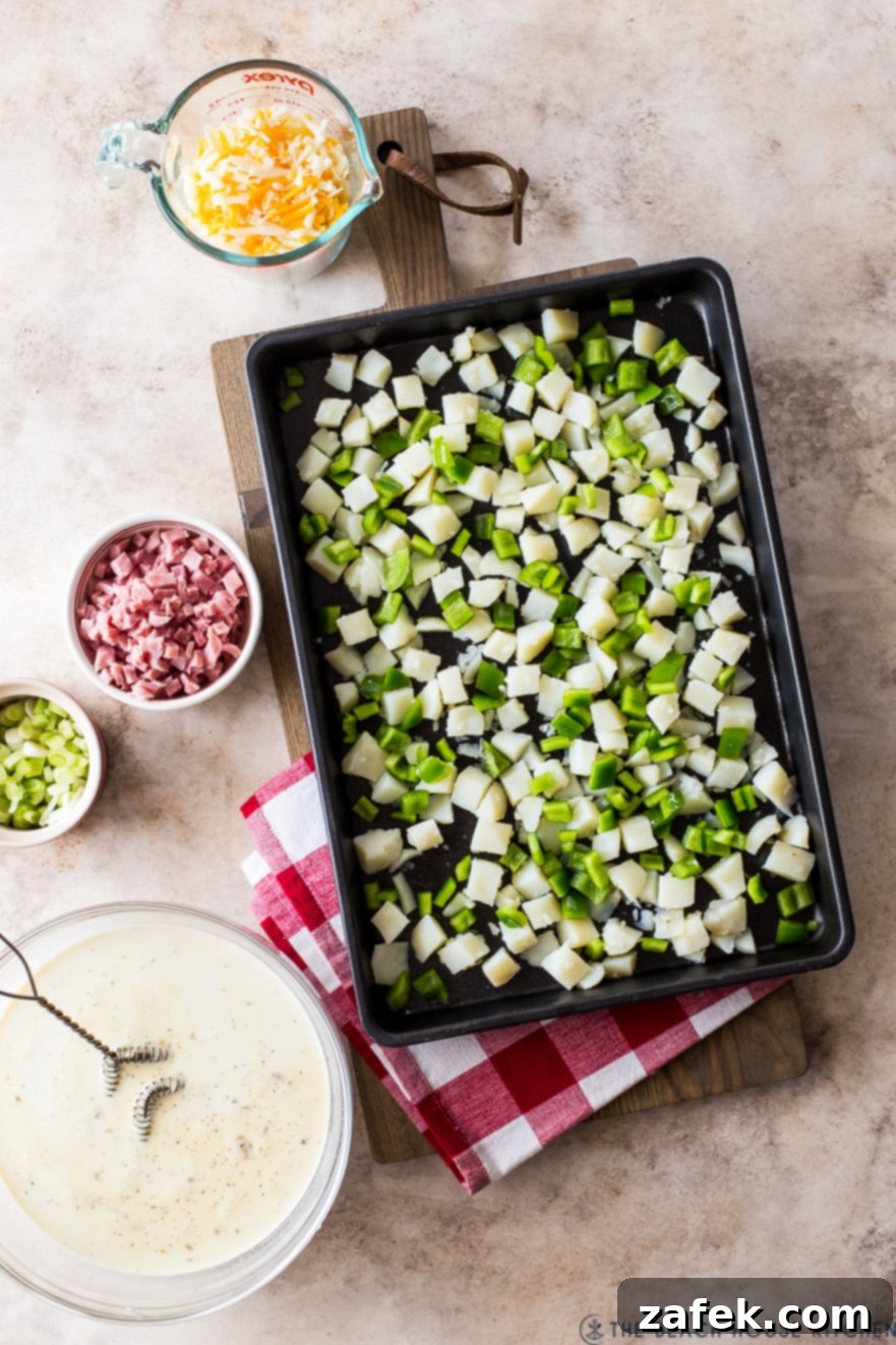 Overhead photo of a sheet pan with cubed potatoes and green peppers, with other bowls filled with denver omelette ingredients ready for assembly