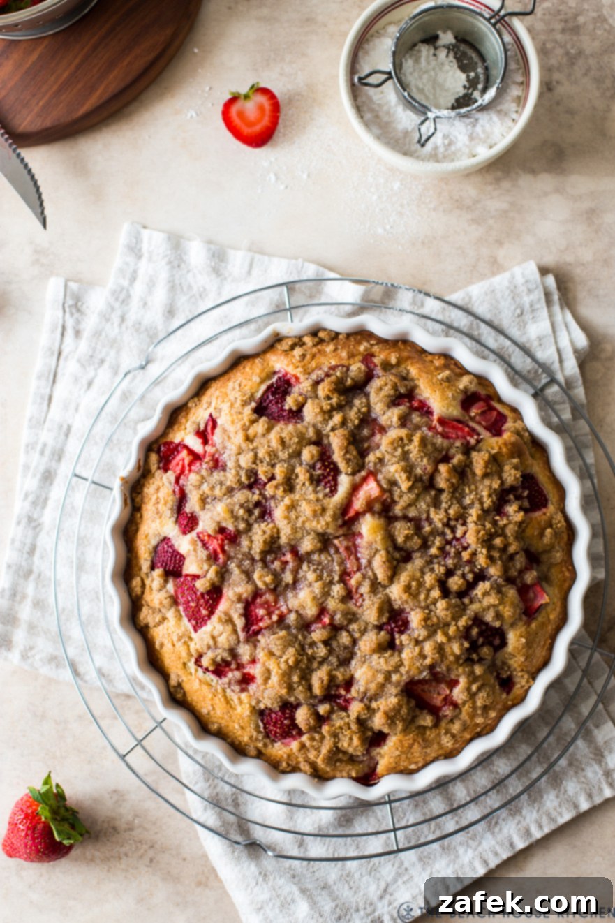 Sweet Strawberry Streusel 2 Deliciously baked strawberry buckle with a golden streusel topping and vibrant strawberries, served in a round white baking dish, ready to be enjoyed.