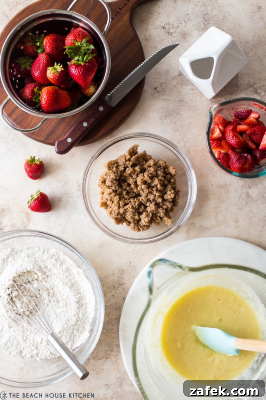 Sweet Strawberry Streusel 7 An organized overhead display of all the essential ingredients for a homemade Strawberry Buckle: flour, sugar, butter, eggs, milk, cinnamon, baking powder, salt, and fresh, vibrant strawberries, neatly arranged in bowls.