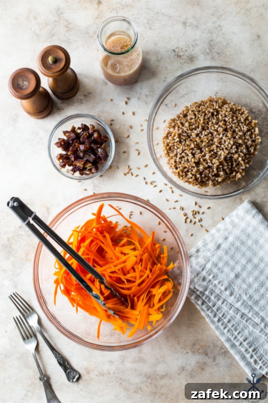 Farro and Carrot Salad with Maple-Date Vinaigrette 5 Overhead photo displaying the individual fresh ingredients for the Carrot Farro Salad: a bowl of vibrant shredded carrots, a bowl of cooked farro, and a bowl of sweet, chopped Medjool dates, neatly arranged.