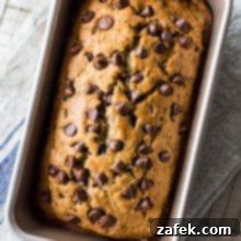Decadent Chocolate Chip Zucchini Loaf 11 Overhead photo of a loaf of chocolate chip zucchini bread, garnished with extra chocolate chips.