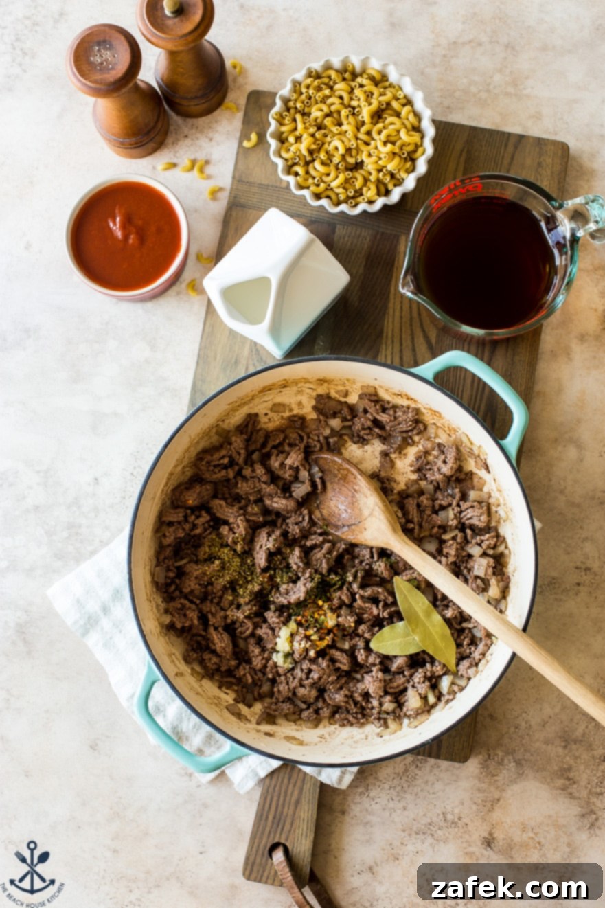 Homemade Greek Beef and Orzo Skillet 6 Overhead photo of a skillet of ground beef surrounded by other ingredients for hamburger helper dish