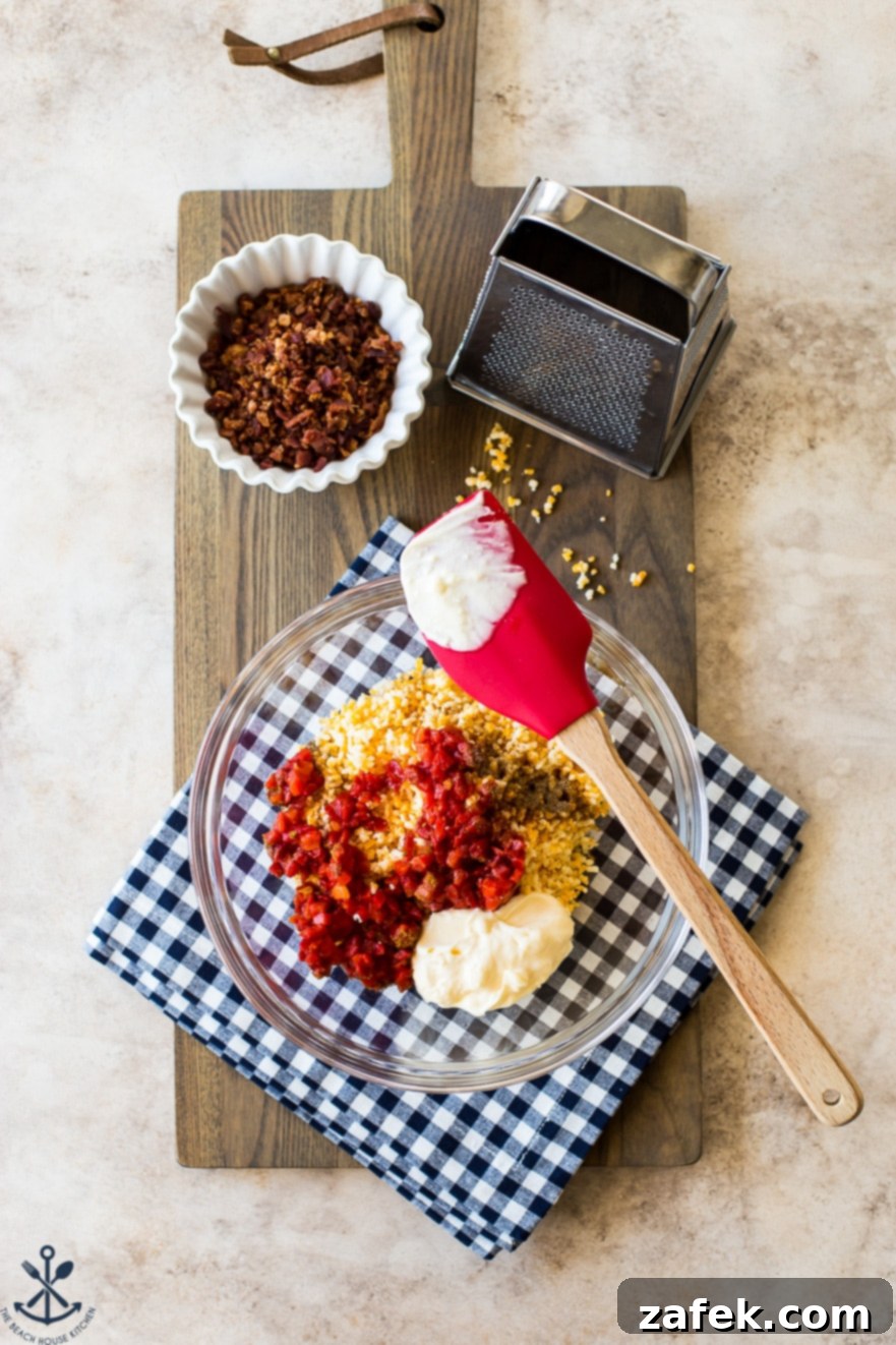 Bacon Pimento Cheese Poppers 6 Overhead photo of a bowl with pimento cheese ingredients with a small bowl of bacon and a grater all on a wooden board