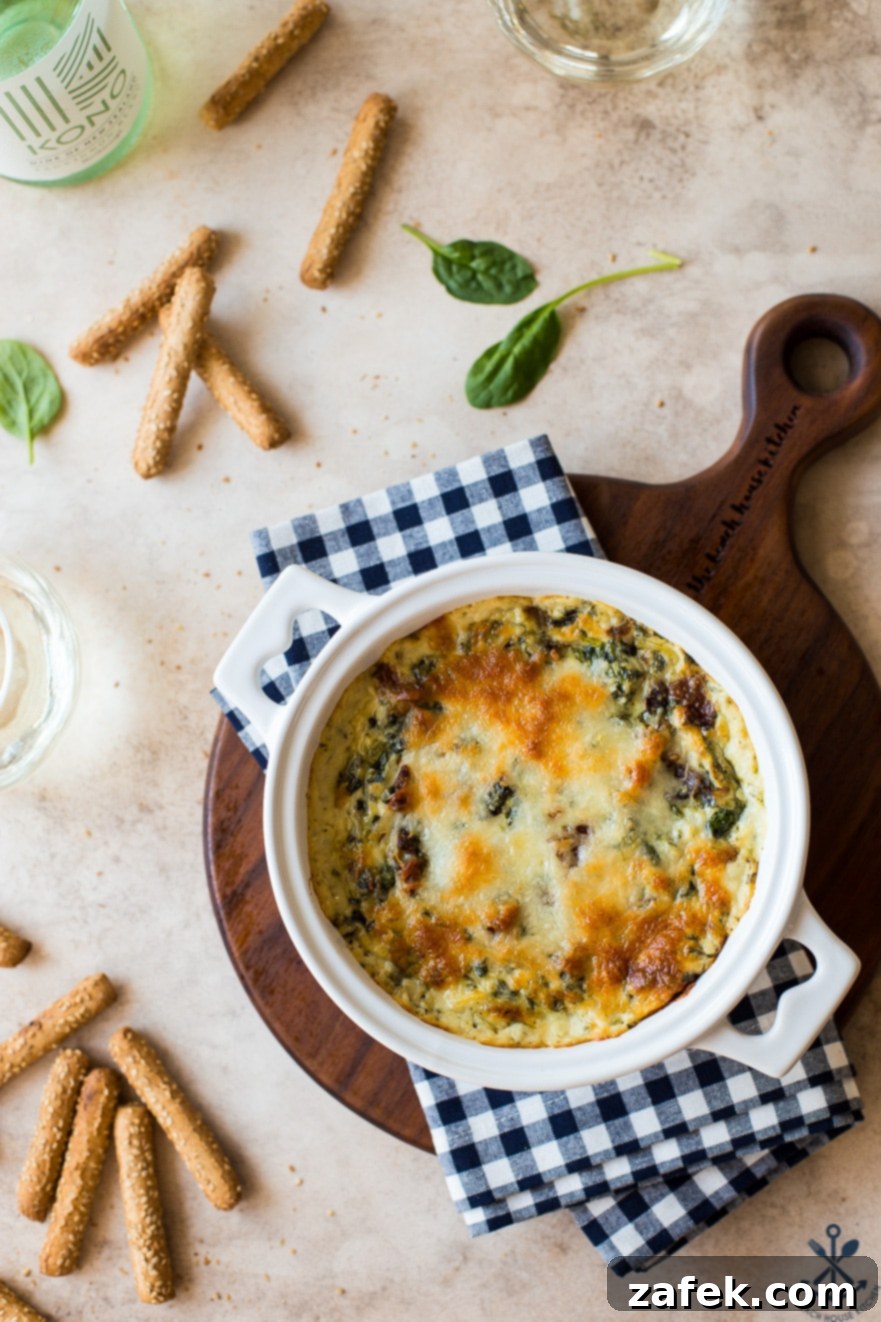 Ultimate Bacon Spinach Artichoke Dip 4 Up-close overhead photo of golden-brown, bubbly cheesy spinach artichoke dip in a white baking dish, fresh out of the oven