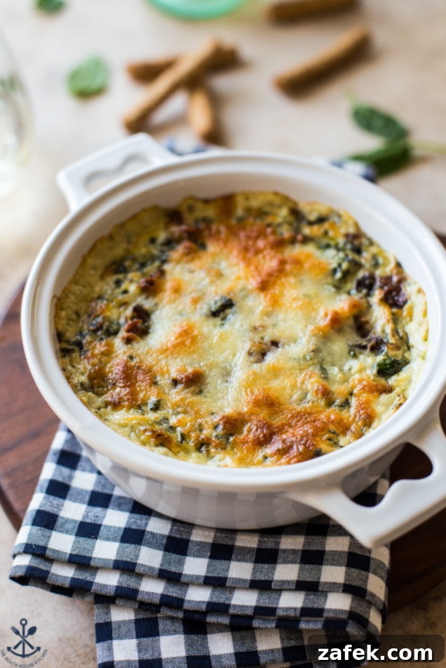 Ultimate Bacon Spinach Artichoke Dip 5 Up close photo of bubbly, golden-brown spinach artichoke dip with visible bacon pieces, scooped with a serving spoon
