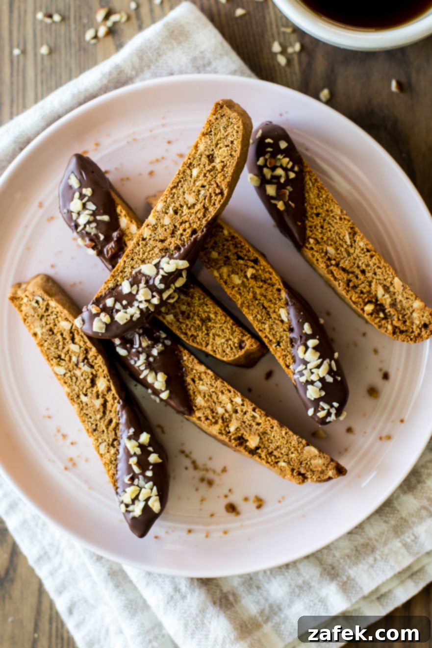 Slices of Chocolate Dipped Hazelnut Espresso Biscotti on a pink plate, showcasing their rustic texture and chocolate coating