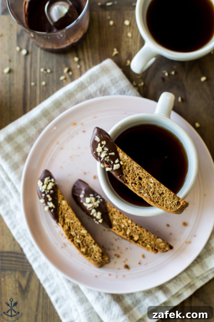 Overhead photo of a single slice of biscotti perfectly balanced on the rim of a coffee cup, highlighting its dunking potential