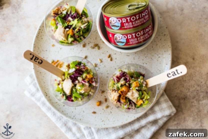 Components for Thai Chili Mango Tuna Chopped Salad: salad in cups and two cans of albacore tuna, illustrating meal prep.