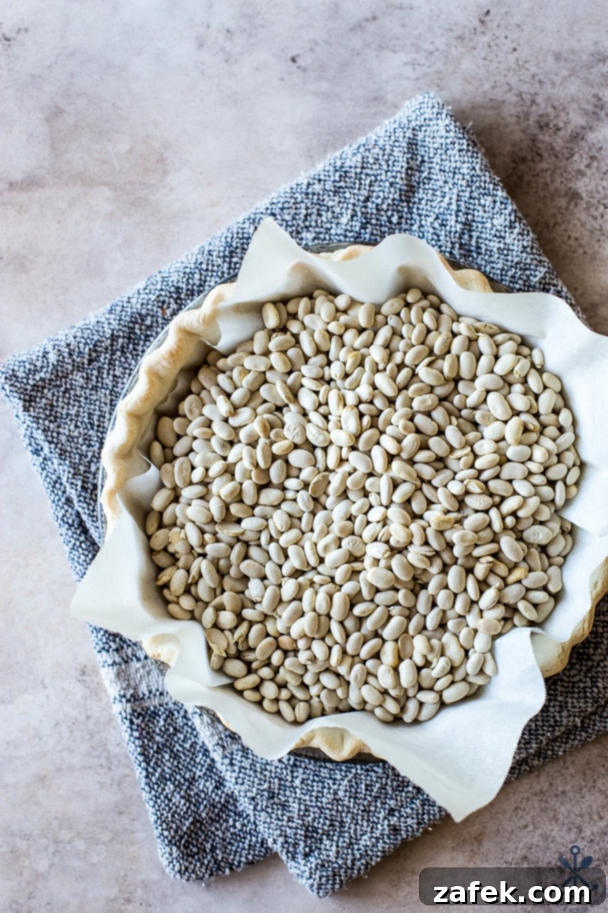 Sweet Potato Pie, Crowned with Pecans 4 Overhead photo of a pie shell, perfectly lined with parchment paper and filled with dried beans for blind baking, resting on a baking sheet.