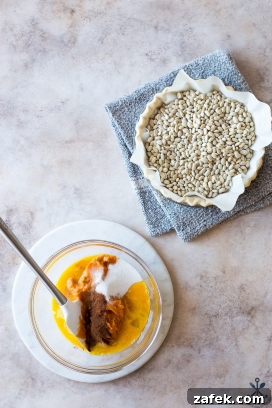 Sweet Potato Pie, Crowned with Pecans 5 Overhead photo depicting a pie crust filled with dried beans and a separate bowl brimming with the smooth, orange sweet potato pie filling, ready to be combined.