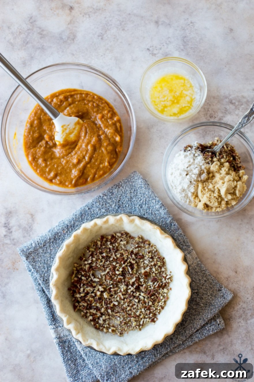 Sweet Potato Pie, Crowned with Pecans 6 Overhead photo showing a pre-baked pie crust, its base sprinkled with chopped pecans, alongside bowls holding ingredients for both the sweet potato filling and the crunchy pecan topping.