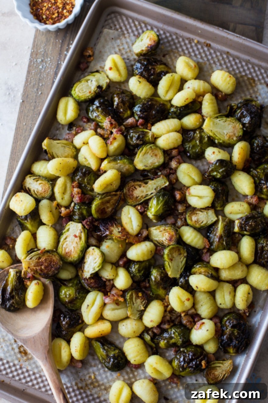 One-Pan Gnocchi Feast with Pancetta and Roasted Brussels 3 Up close overhead photo of a sheet pan filled with baked potato gnocchi, vibrant Brussels sprouts, and crispy pancetta, freshly roasted